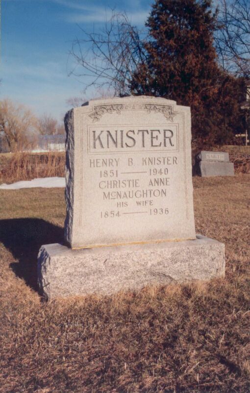 A photo of a rectangular light grey gravestone placed on a slab of light pink stone taken in winter. 