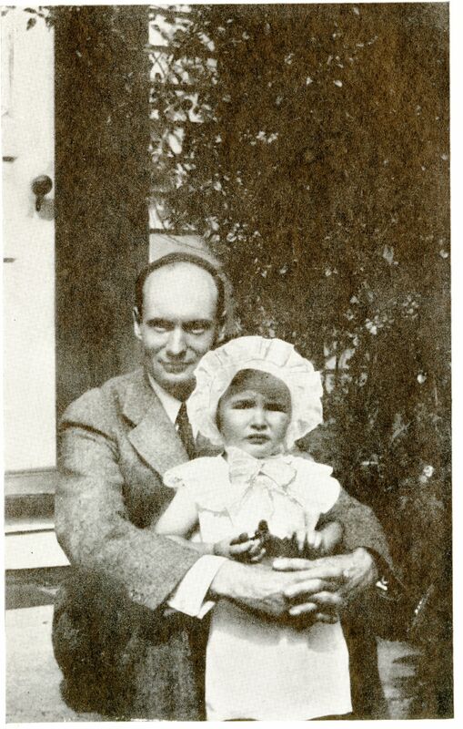 A black and white photo of Raymond Knister sitting in a suit, holding his daughter, Imogen, who is standing in front of him. He is smiling and she is squinting at the camera. 